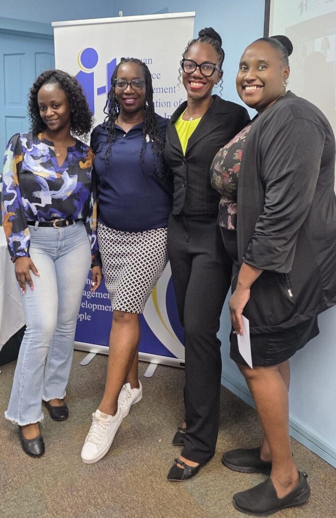 Four HRMAB members smiling together in front of the association's banner