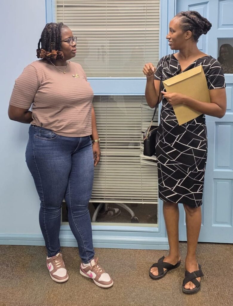 Two HR professionals in conversation, one holding a membership envelope